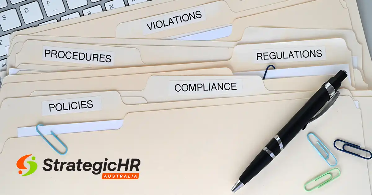 Several file folders labelled Procedures, Violations, Regulations, Policies, and Compliance are spread out on a desk with paperclips, a pen, a keyboard, and the StrategicHR Australia logo visible—highlighting an organised performance management process.