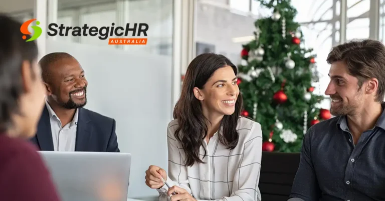 Four people sit around a table in an office, engaged in conversation about employee wellbeing. A decorated Christmas tree is in the background. The Strategic HR Australia logo is visible in the top left corner.