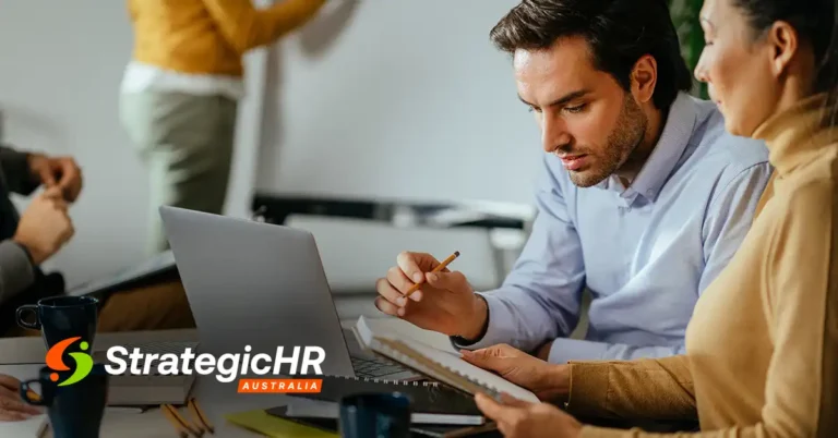 Two people sit at a table working together, looking at a laptop and new employment law documents. Coffee mugs are placed on the desk. The Strategic HR Australia logo is visible in the lower left corner.
